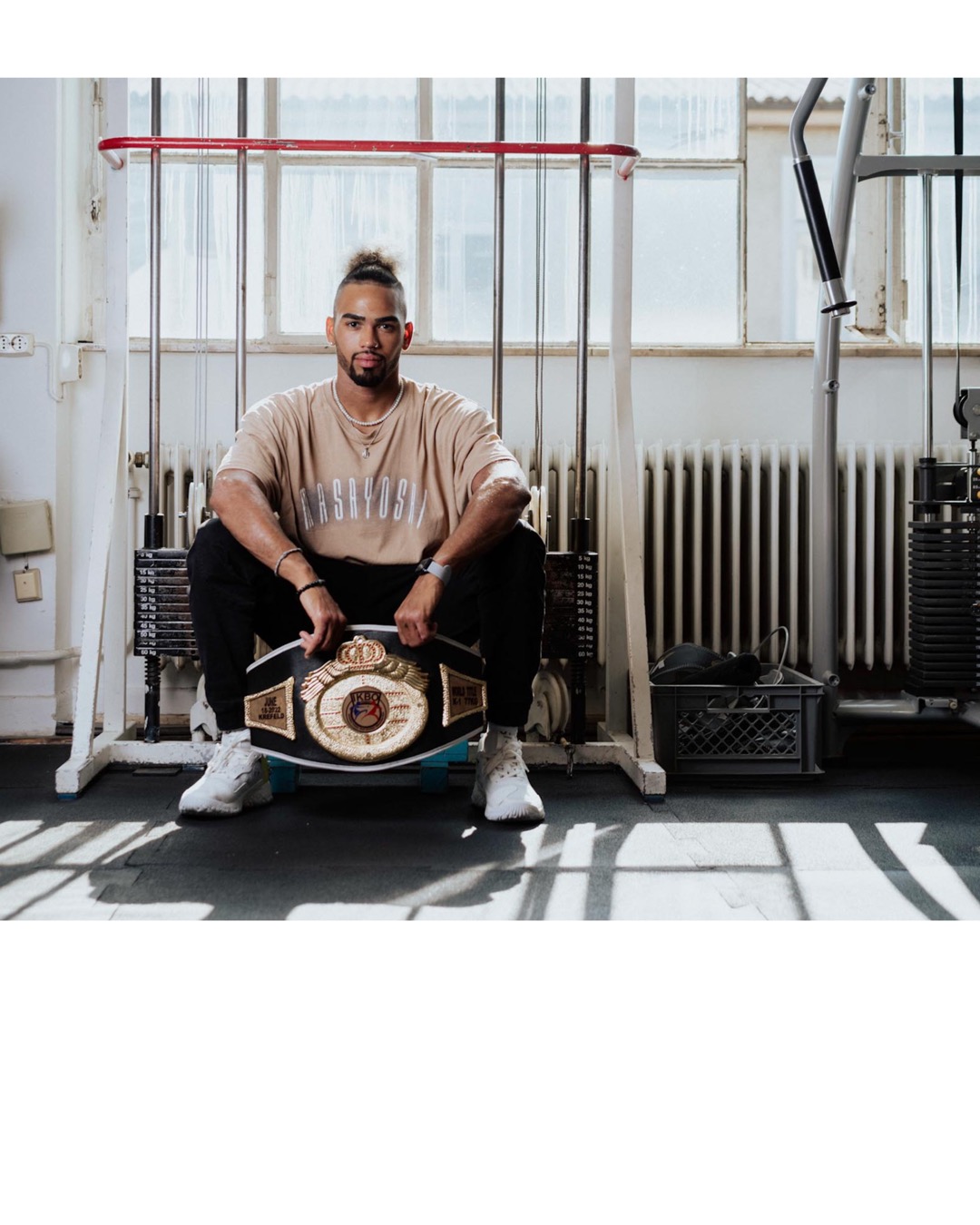 Environmental Lifestyle portrait of Dani Traore in his kickboxing studio in Reutlingen holding his champion belt captured by Lifestyle Photographer Nadine Wilmanns