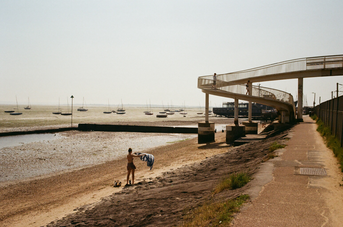 Woman shaking towel at beach of Leigh-on-Sea