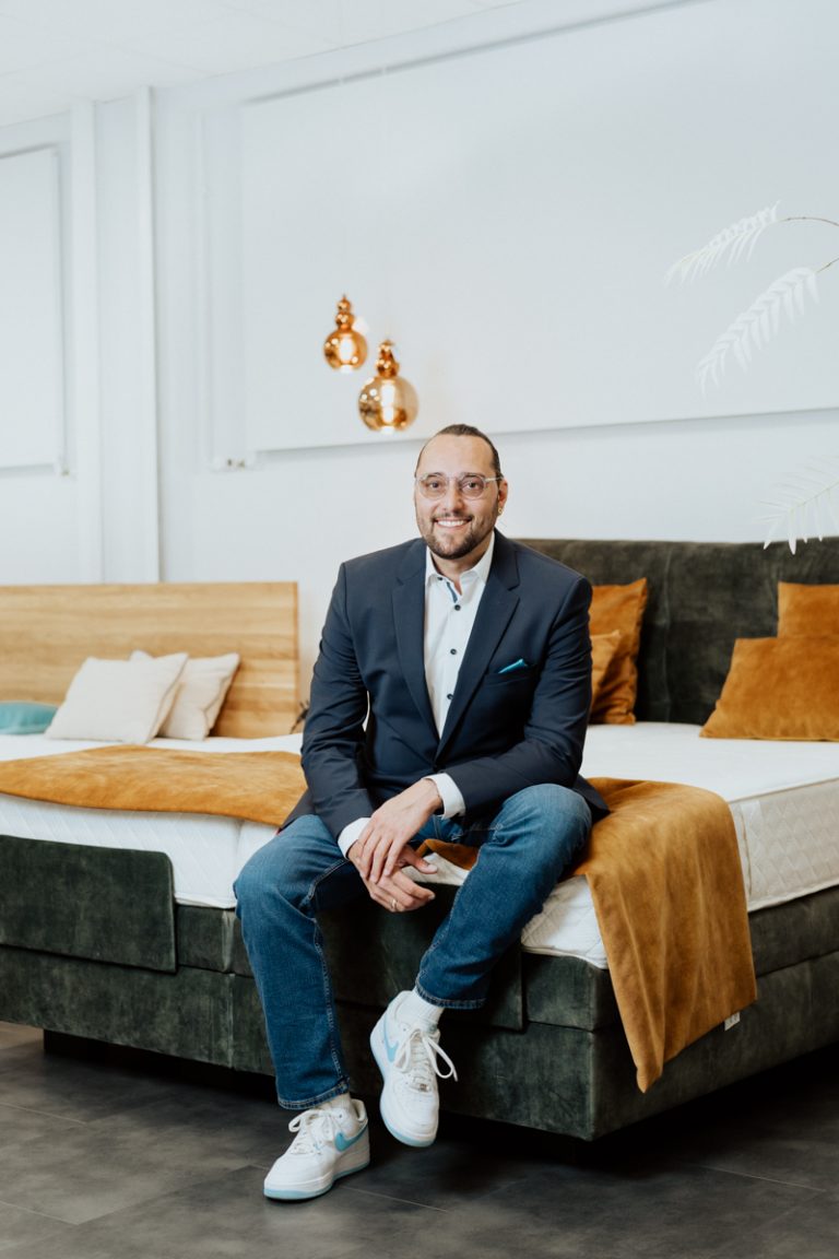 Editorial Lifestyle Portrait of sleep expert Daniel Amann sitting on a bed in his shop