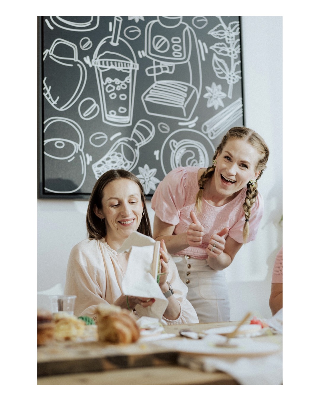 Maria Voropayeva, founder of Punch and Loop, smiling at the camera while another woman is holding a colorful punch needle craft frame.