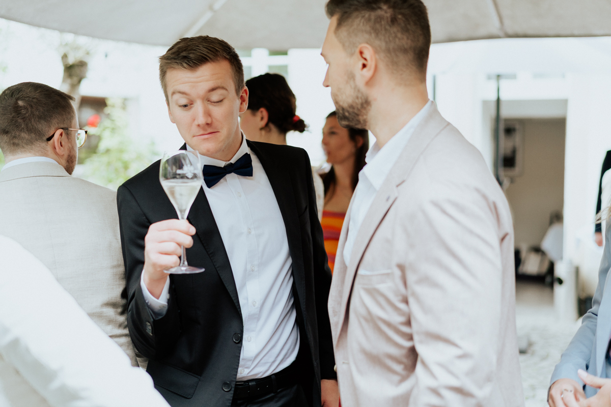Wedding guest looking humorously into his drink glass in Reutlingen / Hochzeitsgast blickt humorvoll in sein Glas bei der Feier in Reutlingen