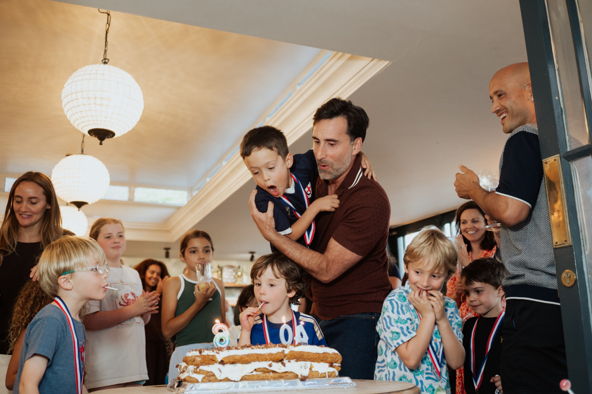 Birthday man with his son blowing out birthday cake candles in London / Vater bläst mit seinem Sohn die Kerzen auf der Geburtstagstorte aus