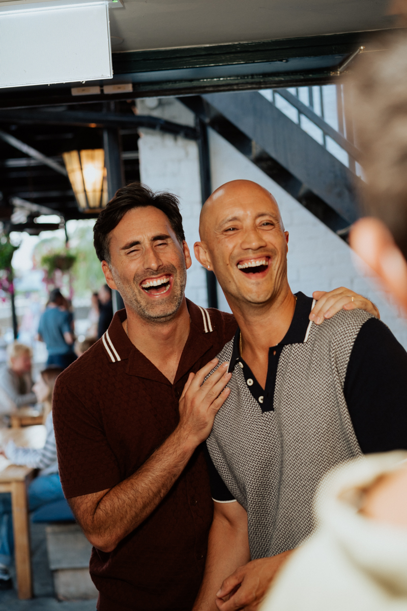 Two men laughing heartily at London birthday party in Hammersmith pub / Zwei Männer lachen herzlich bei einer Geburtstagsfeier in London