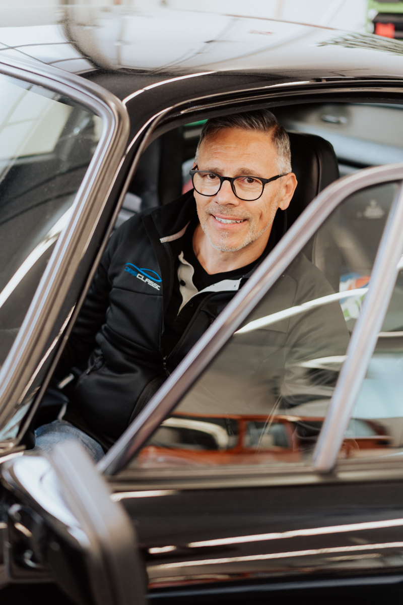 Dietmar Brunner automotive expert at DBS Classic in professional headshot in his car on location in Mössingen and discussing business defining moments